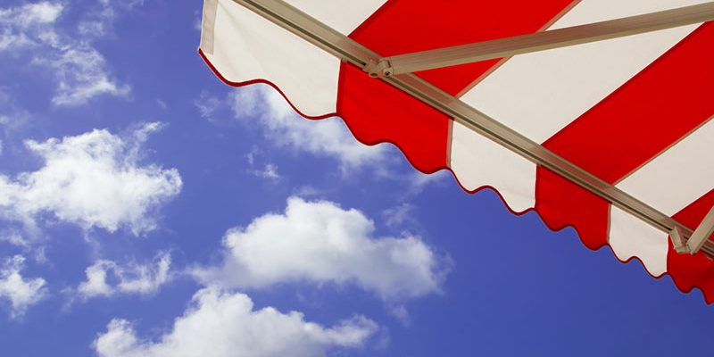 red and white striped awning with bright blue sky behind